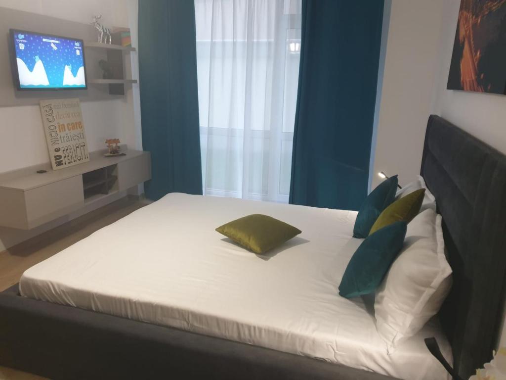 a bedroom with a bed with pillows and a television at Body Residence in Mamaia Nord