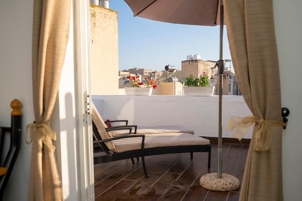 un balcón con una silla y una sombrilla en el techo en Seaside Apartments Malta Sliema 1, en Sliema