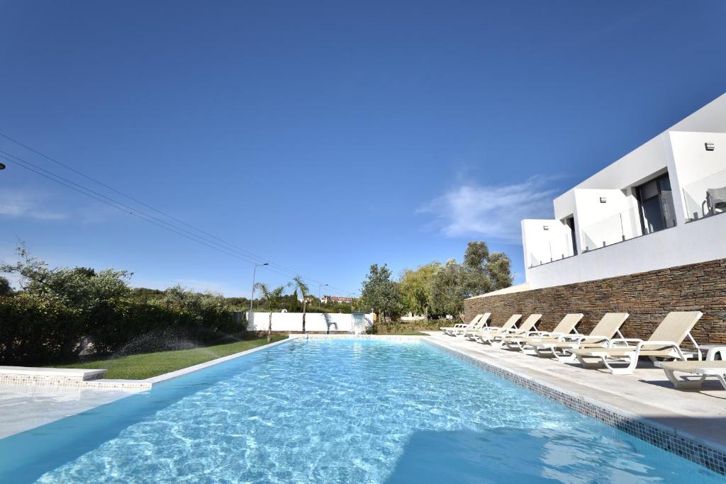 a swimming pool with chairs and a building at Quinta Solar da Portela in Almodôvar