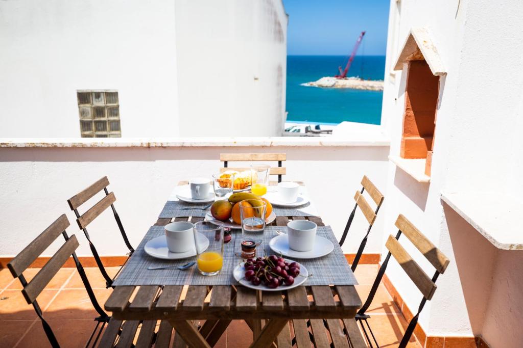 uma mesa de madeira com fruta e sumo numa varanda em Harbour House na Ericeira