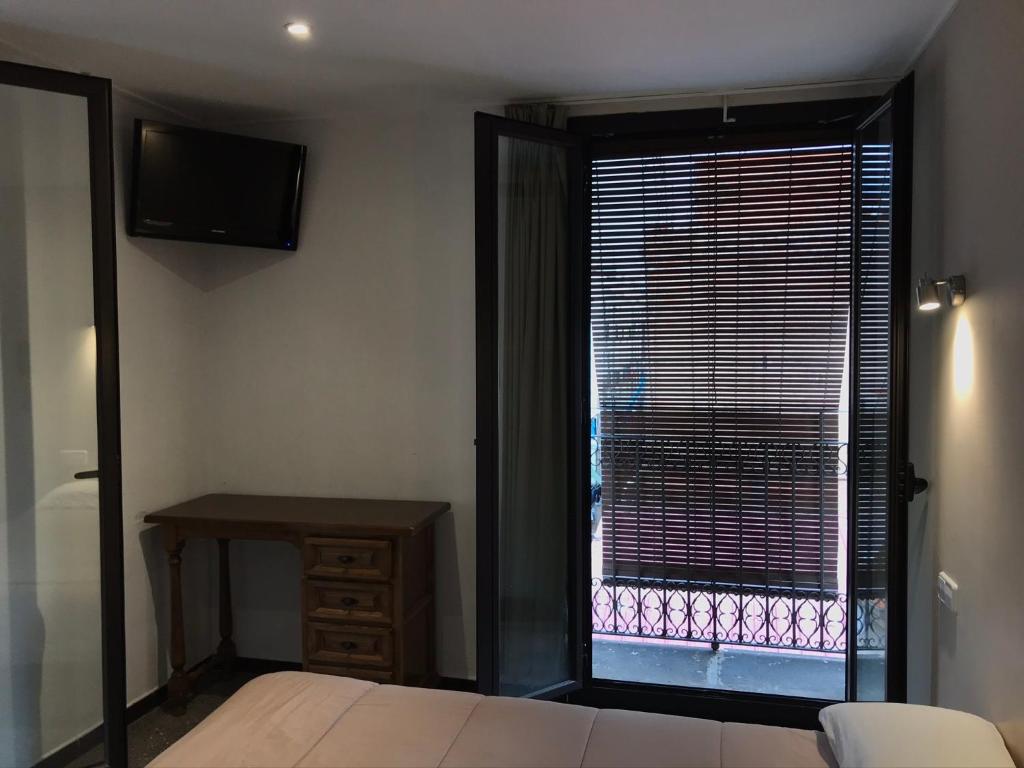 a bedroom with a window with a bed and a desk at Hostal Radio Barcelona in Barcelona