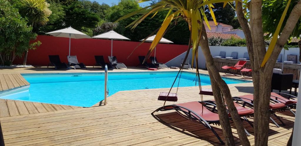 einen Pool mit Stühlen und Sonnenschirmen auf einer Holzterrasse in der Unterkunft La Villa en L'île - 2 Piscines & Spa in Noirmoutier-en-l'lle