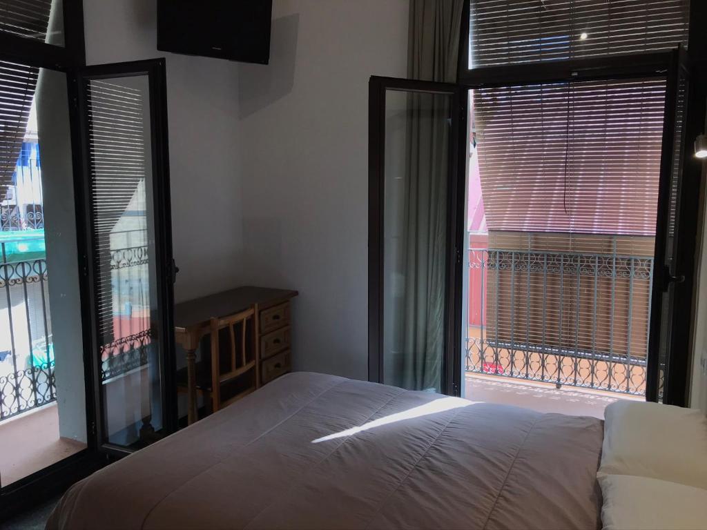 a bedroom with a bed and two large windows at Hostal Radio Barcelona in Barcelona