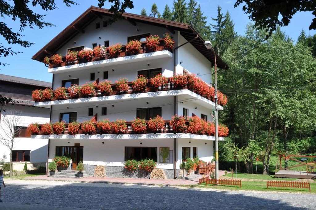 a white building with red flowers on the balconies at Pensiunea Anotimpuri in Predeal
