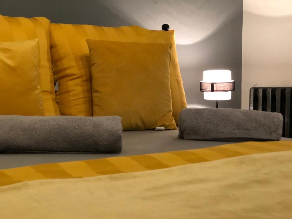 1 dormitorio con 1 cama con almohadas amarillas y lámpara en Apart Rooms Sova, en Novi Sad