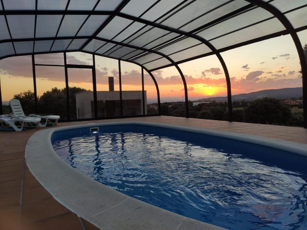 a swimming pool under a roof with a sunset in the background at Casa Rural El Coscojar in Teruel