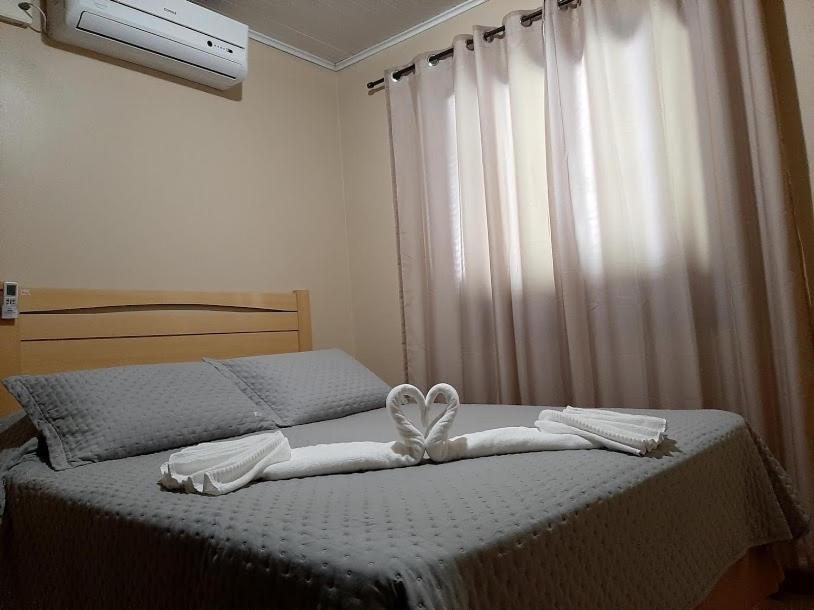 ein Bett mit zwei Handtüchern und einer Schleife darauf in der Unterkunft Casa da Cris/Marcelo in Gramado