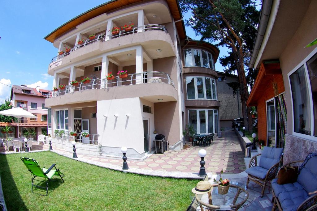 a large house with a patio and a yard at Приятелската къща in Velingrad