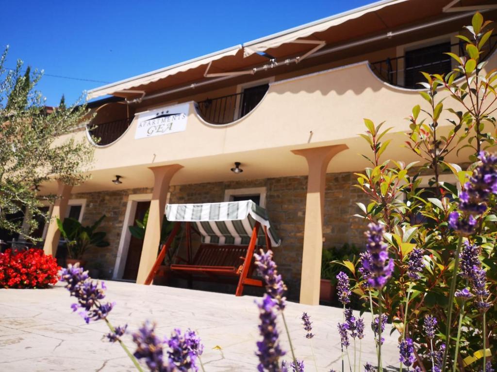 une maison avec des fleurs violettes devant elle dans l'établissement Apartments Gea, à Lucija
