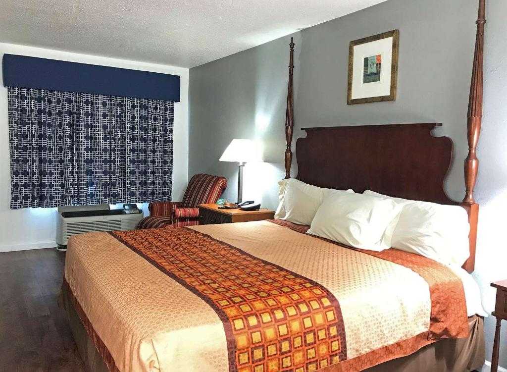 um quarto de hotel com uma cama grande e uma cadeira em American Inn & Suites Russellville em Russellville