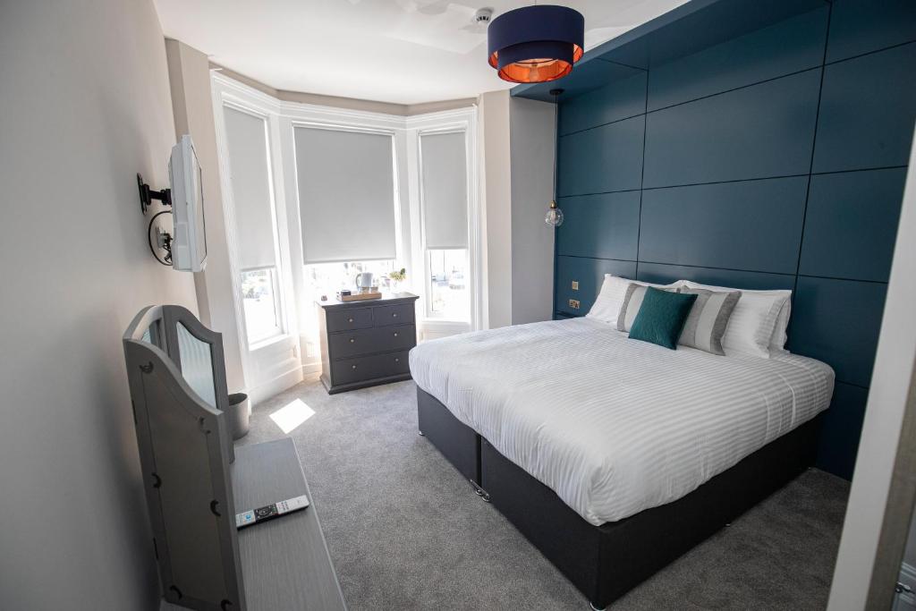 a blue bedroom with a bed and a window at Lynwood House in Southport