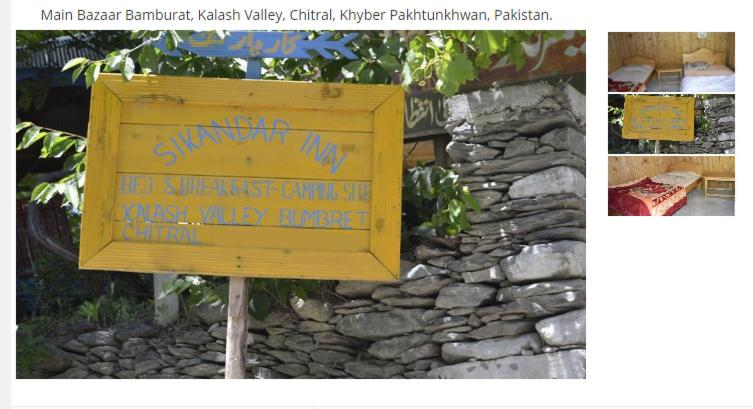 a yellow sign in front of a stone wall at Sikander Inn Chitral in Anīahgrām