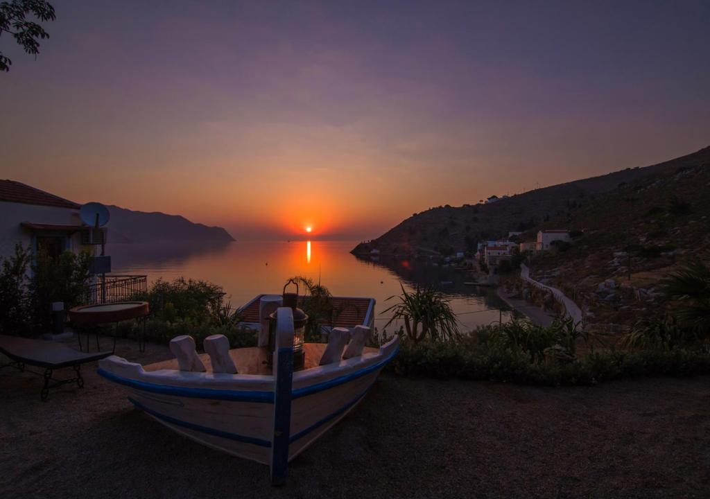 a boat sitting on the side of a lake at sunset at Niriides Hotel Apartments in Symi