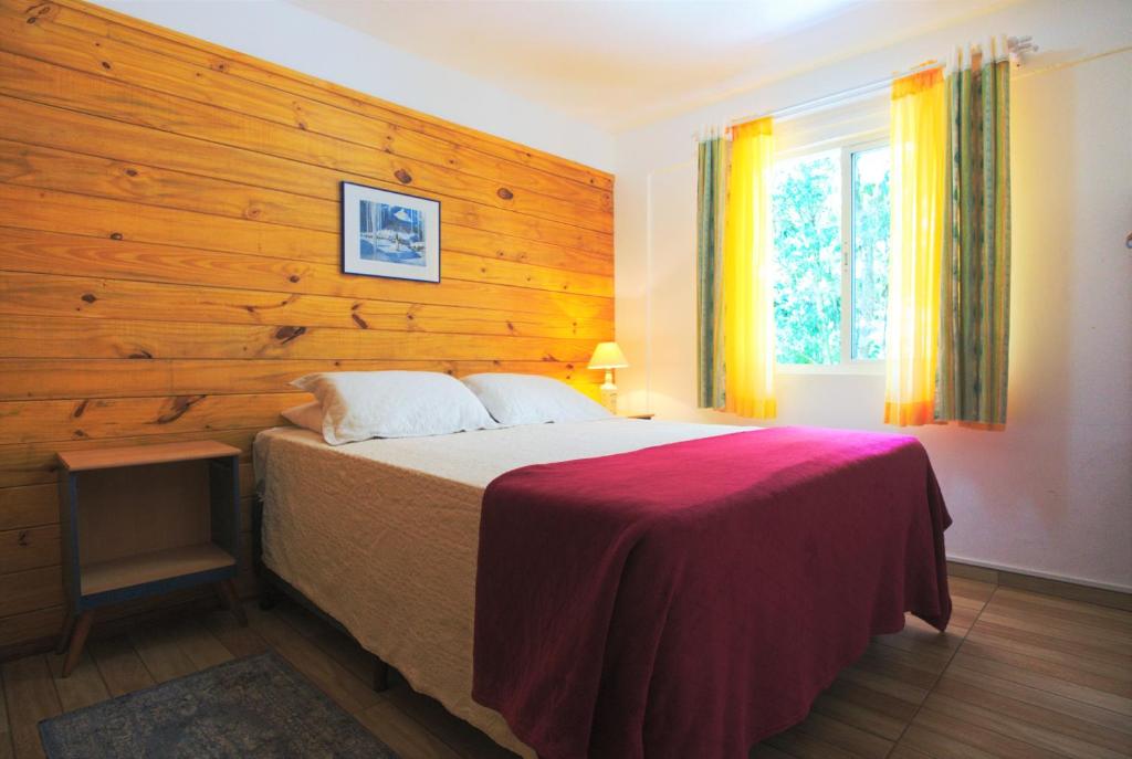 a bedroom with a bed with a wooden wall at Hospedaria Brigite - Apartamento de Férias in Treze Tílias