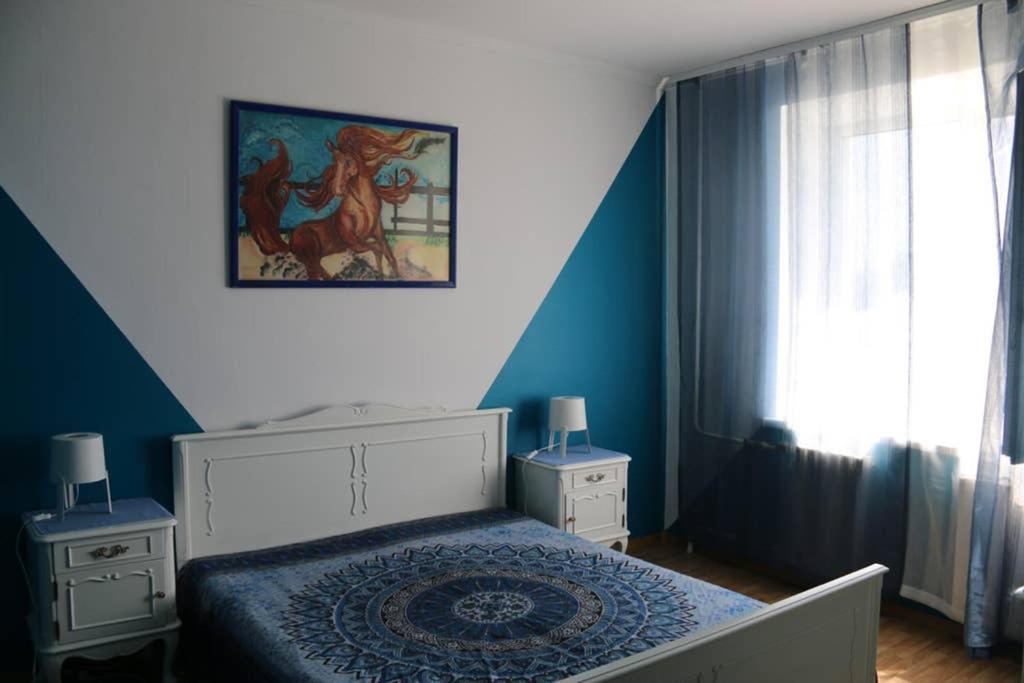 een slaapkamer met een bed en een schilderij aan de muur bij Апартаменти на Космонавтів in Vinnytsya