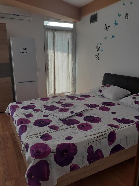 Un dormitorio con una cama con flores púrpuras. en Apartament Daniel en Eforie Nord