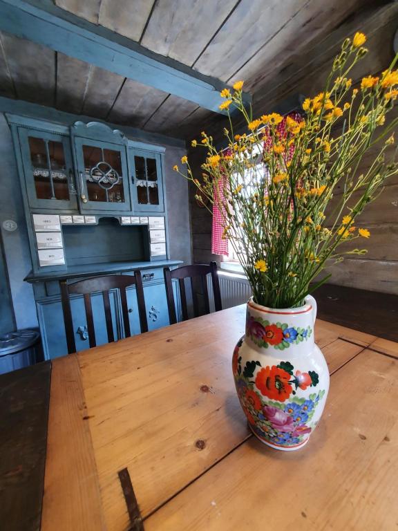 un jarrón lleno de flores sentado en una mesa de madera en Chalupa Království en Šluknov