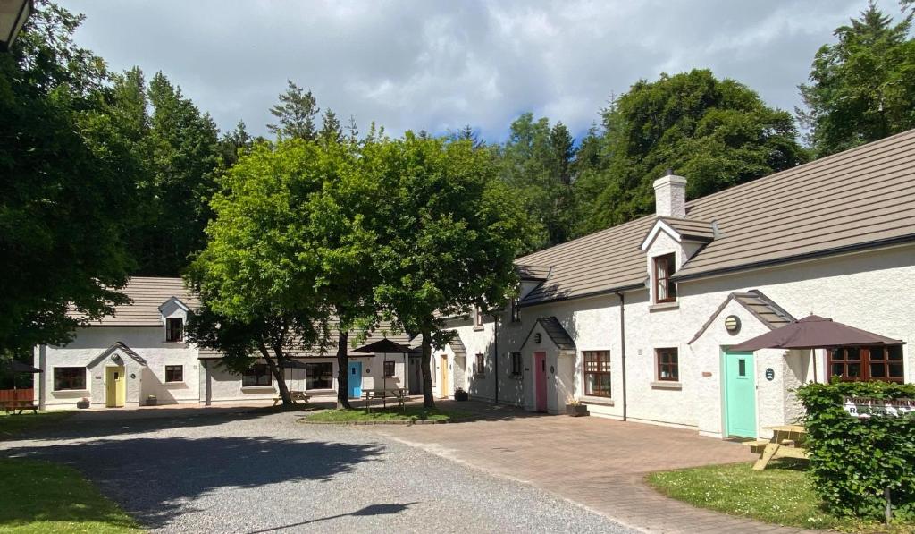 un groupe de bâtiments blancs avec des arbres en arrière-plan dans l'établissement Tully Mill Cottages, à Bellanaleck