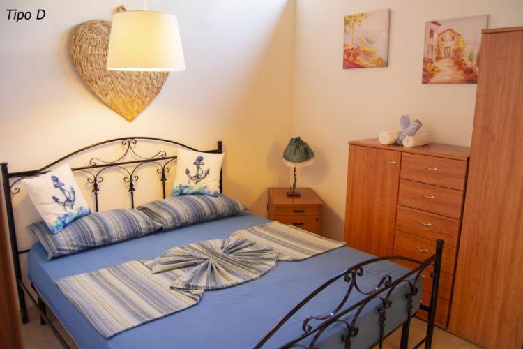 Schlafzimmer mit einem Bett mit blauer Bettwäsche und einer Kommode in der Unterkunft Villetta Francesca in Marina di Camerota