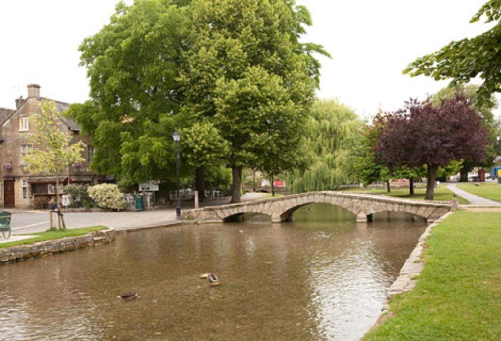a bridge over a river with ducks in the water at Old Manse Hotel by Greene King Inns in Bourton on the Water