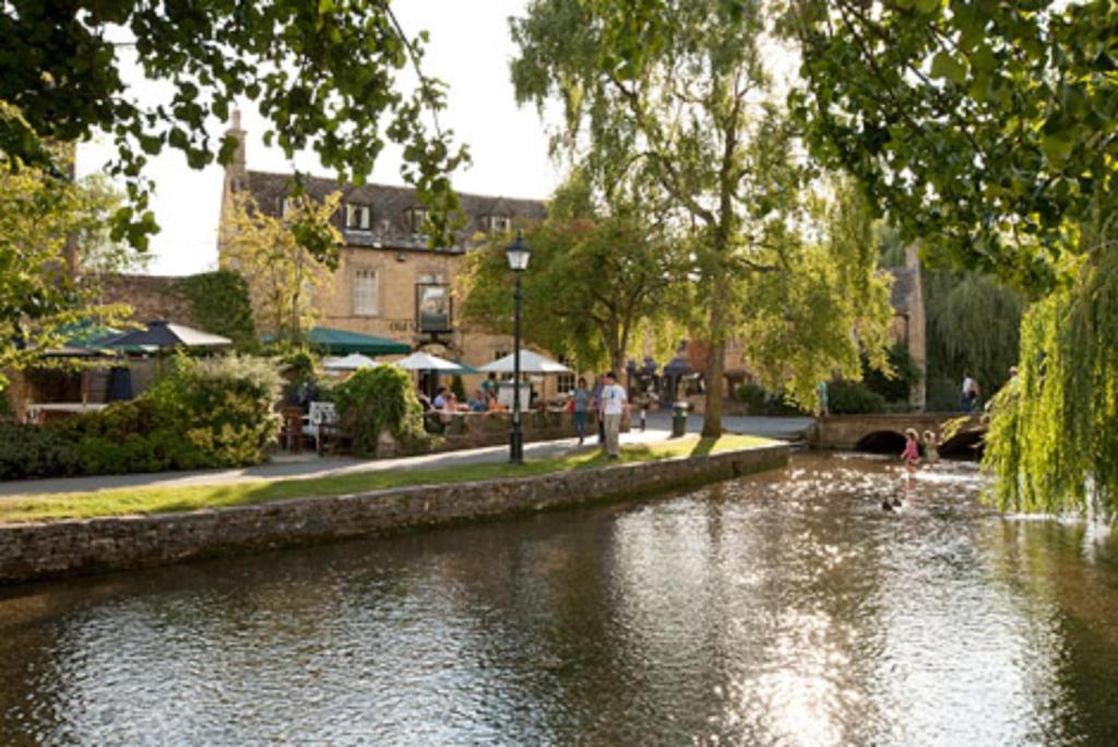 a river in a city with people walking on it at Old Manse Hotel by Greene King Inns in Bourton on the Water