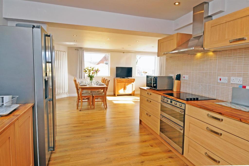 a kitchen with wooden cabinets and a table in it at Whitby Spacious Rugby Field Cottage with off-street parking and EV fast point for electric cars in Whitby