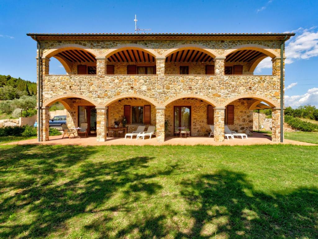 un gran edificio de piedra con un campo de césped delante de él en Belvilla by OYO Casa Oleandri en Suvereto