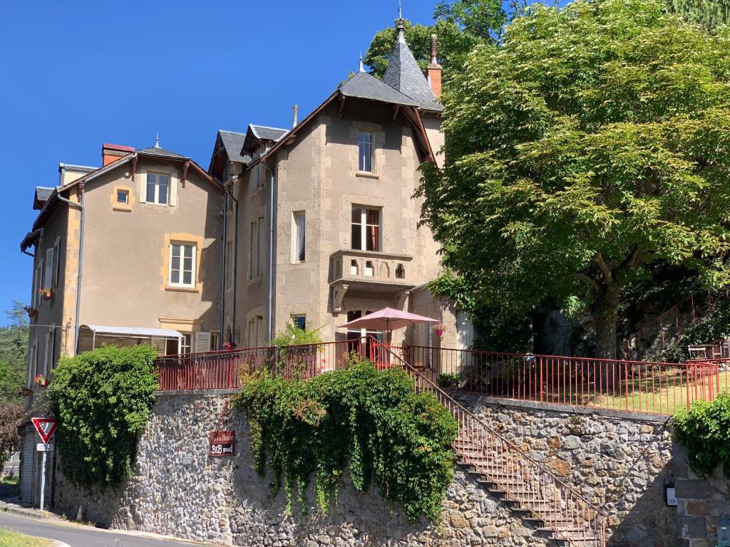 ein großes Gebäude auf einem Hügel mit einer Steinmauer in der Unterkunft Villa St. Hubert in Saint-Nectaire