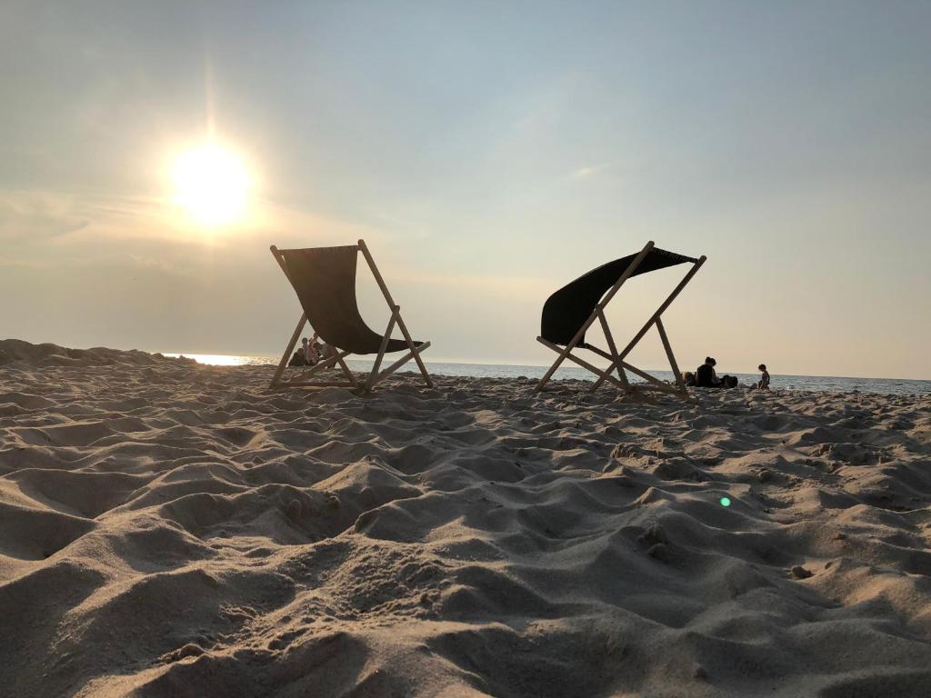 two chairs on a beach with the sun in the background at Apartament Family Beach przy Golden Tulip in Międzyzdroje