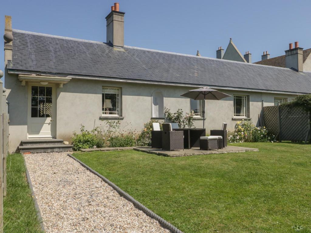 uma casa com uma mesa e cadeiras e um guarda-sol em Maple Cottage em Sturminster Newton