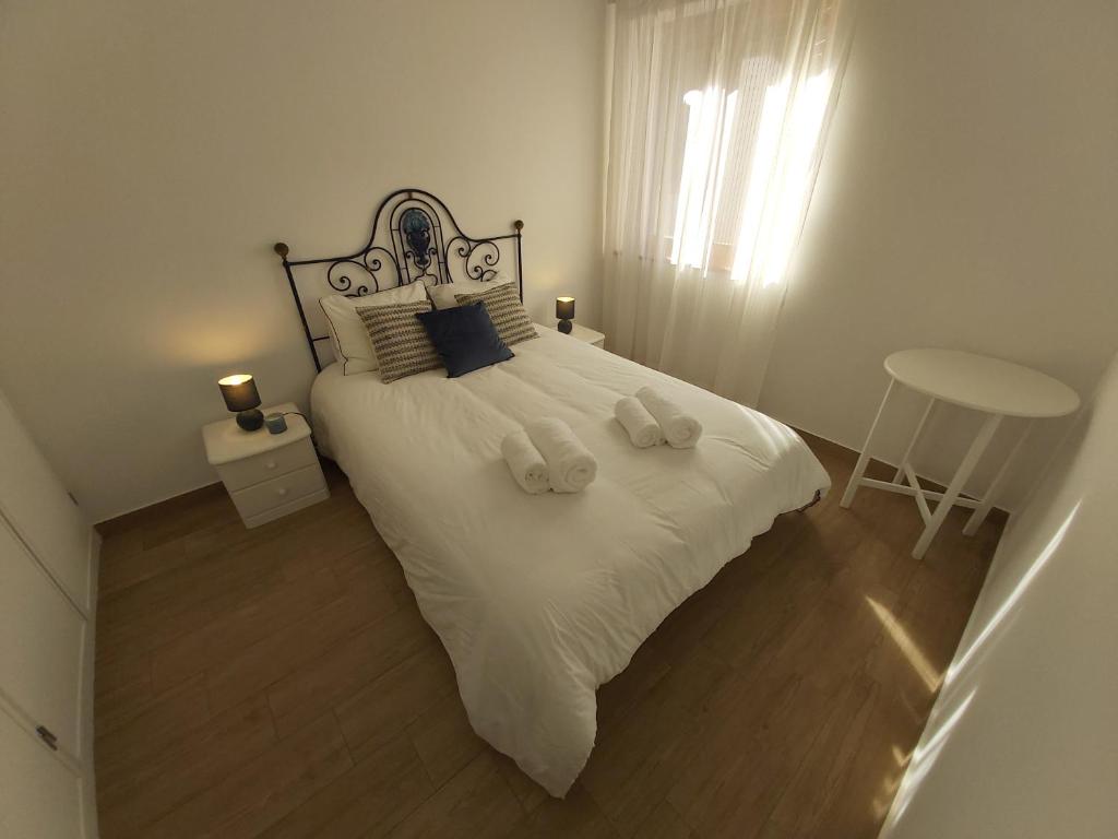 een slaapkamer met een groot wit bed en 2 handdoeken bij Sun and Beach II AC Wifi 90mts from the Beach in Portimão