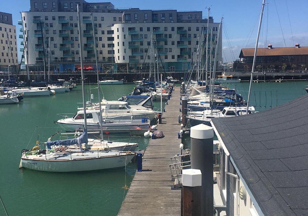 un groupe de bateaux amarrés dans un port de plaisance comportant des bâtiments dans l'établissement Brighton Marina Floating home, à Brighton et Hove