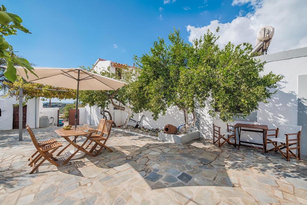 een patio met een tafel en stoelen en een parasol bij Casa La Perla - Lachania in Lachaniá