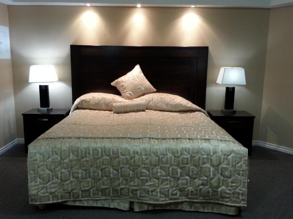 - une chambre avec un grand lit et deux lampes dans l'établissement Sunrise Motel, à Regina