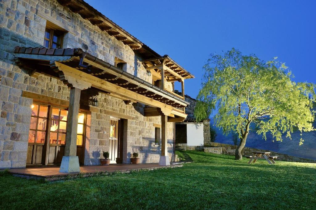 una casa in pietra con un portico e un albero di La Casa de Bustantegua a Selaya