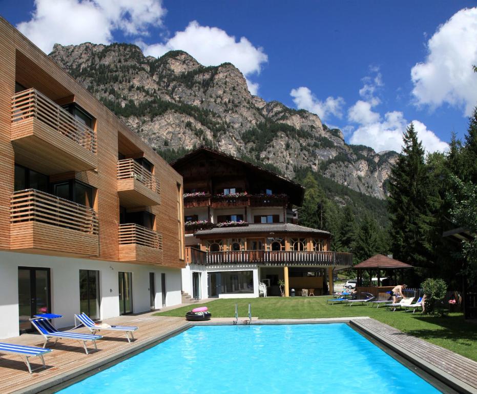 a hotel with a swimming pool in front of a mountain at Hotel Piné in Tires