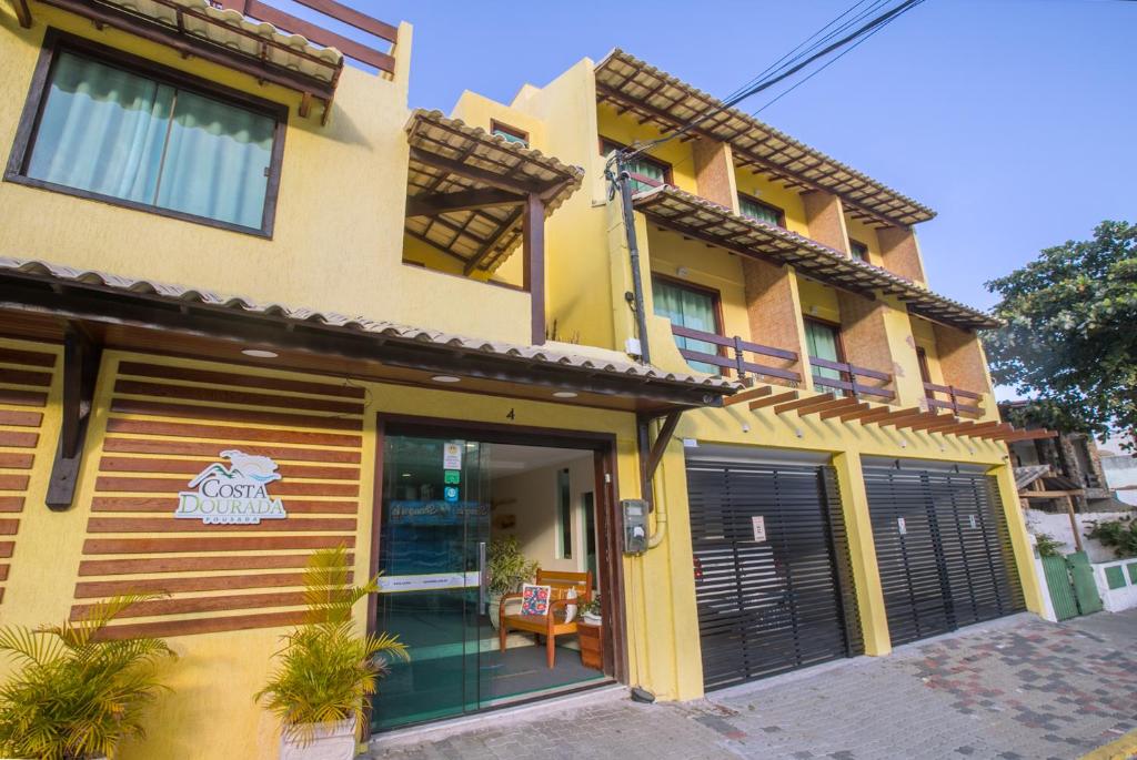 um edifício amarelo com portas e janelas pretas em Costa Dourada Pousada em Arraial do Cabo