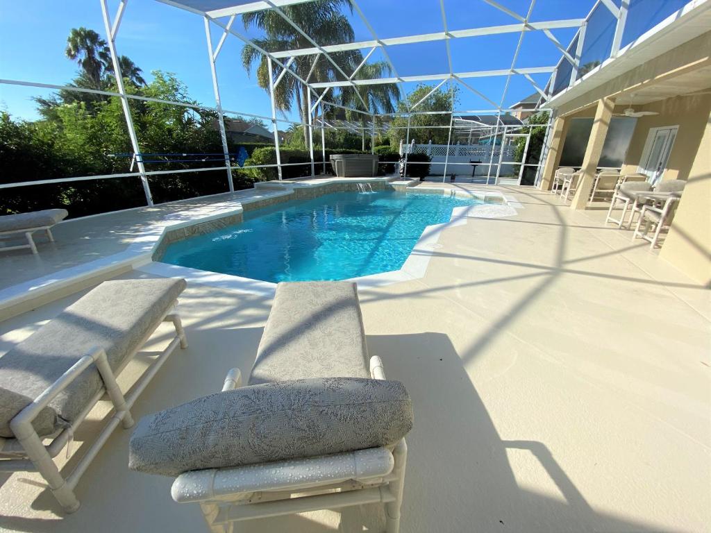 - une piscine avec 2 chaises longues et une chaise longue dans l'établissement Mickeys Pearl - Phenomenal 7BR with 4 Master Suites Privacy Pool & Hot Tub Gas BBQ - 2 miles to Disney, à Orlando