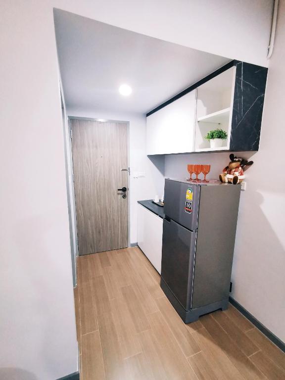 A narrow kitchenette and entryway with a refrigerator, sink and overhead storage.
