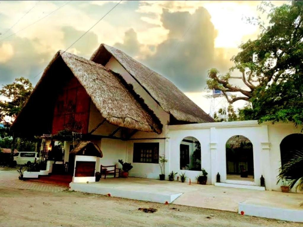 a small white house with a thatched roof at RedDoorz Plus @ Evangeline Beach Resort in Pagudpud