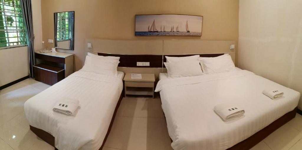 two beds in a hotel room with white sheets at Hemingway Cottage 海明威度假屋 in Semporna