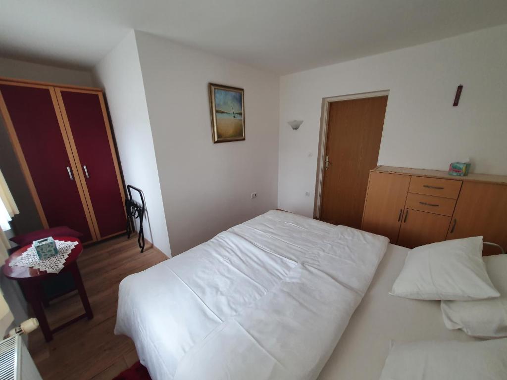 - une chambre avec un lit blanc et une armoire en bois dans l'établissement Apartma Meta, à Radovljica