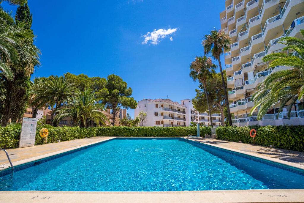 une piscine bordée de palmiers et un bâtiment dans l'établissement Las Palomas Apartments Econotels, à Palma Nova