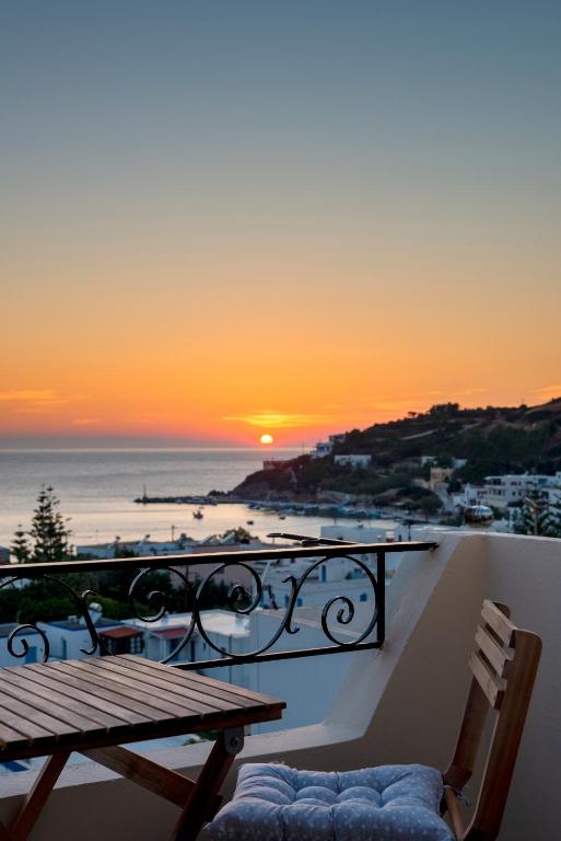 a sunset from a balcony with a table and a bench at Guesthouse ERI in Kini