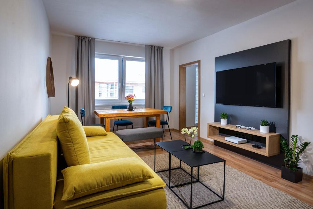 a living room with a yellow couch and a flat screen tv at FLEXIHOME sk - Bellova - Brand New - Neftflix - Private Parking in Liptovský Mikuláš