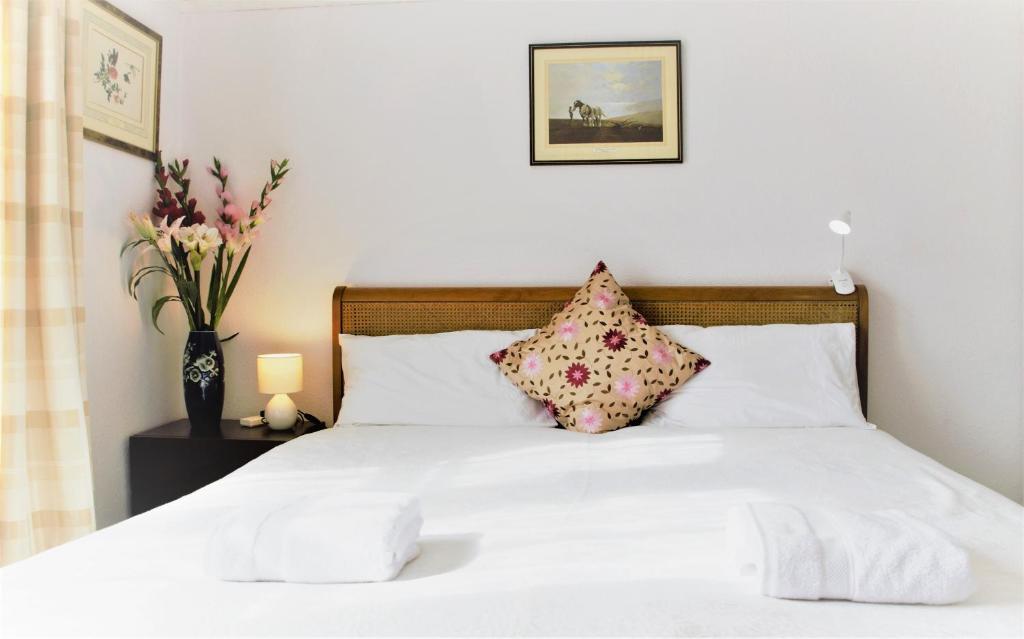 uma cama com lençóis brancos e almofadas num quarto em The Witterings Bed and Breakfast em Chichester