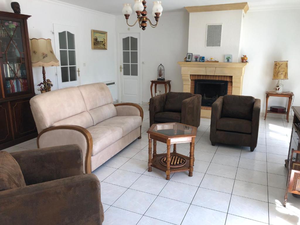 uma sala de estar com um sofá e cadeiras e uma lareira em St Georges de Didonne, Maison bien équipée au calme em Saint-Georges-de-Didonne