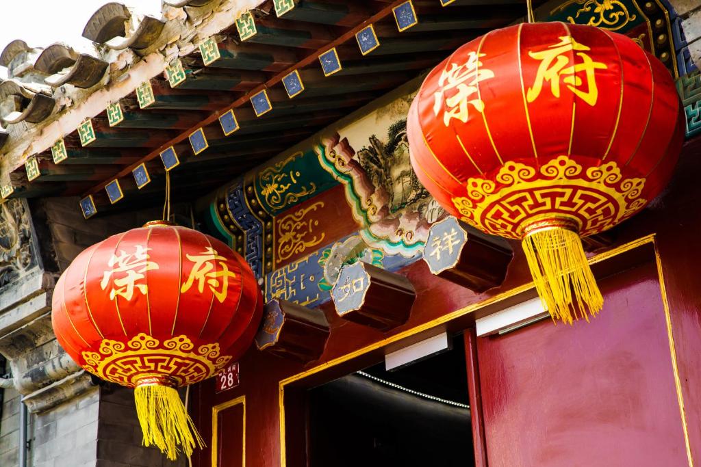 due lanterne rosse sono appese sopra una porta di Beijing Rong Courtyard Boutique Hotel a Pechino
