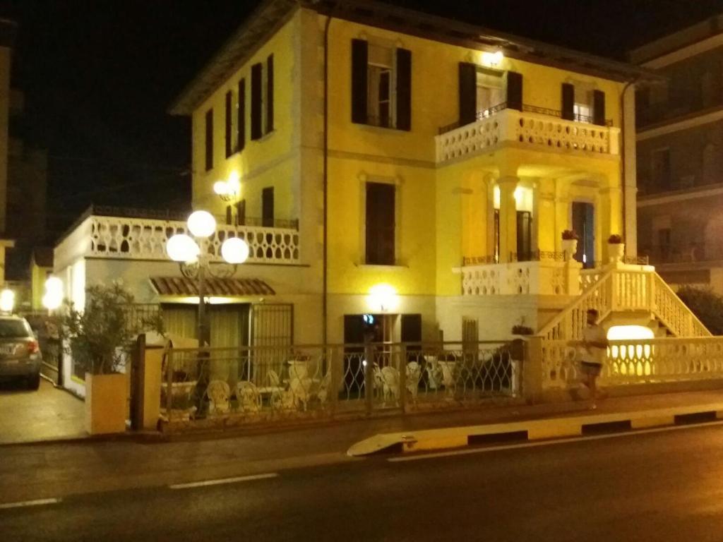 Hotel Villa Laura في ريميني: مبنى اصفر في شارع في الليل