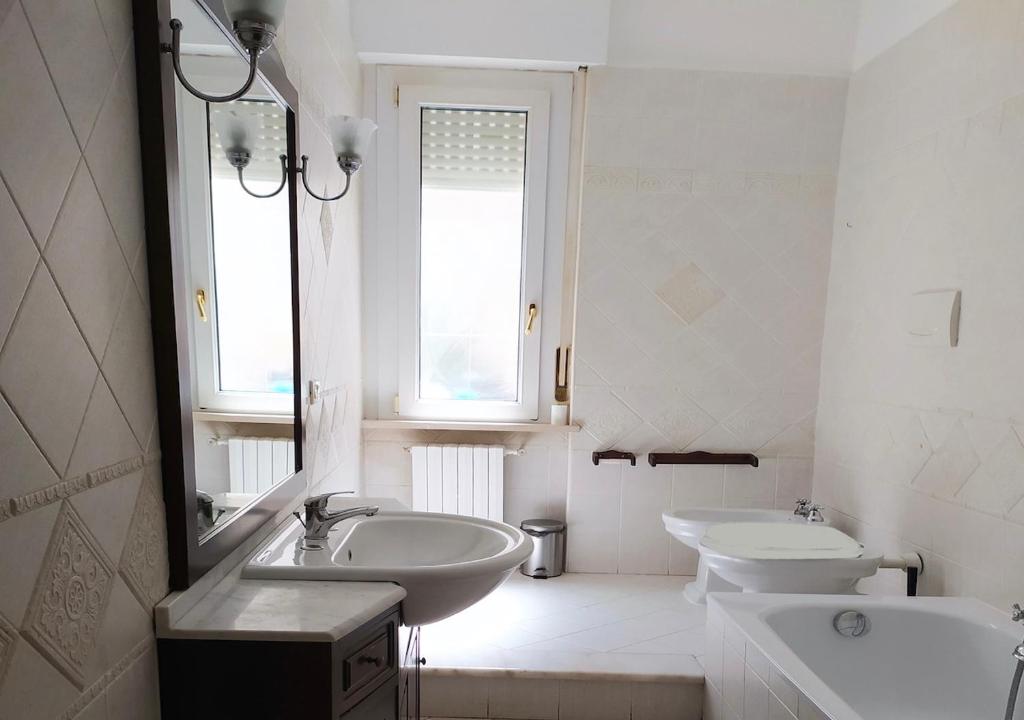 a white bathroom with two sinks and a mirror at Cleo Azalea in Ancona